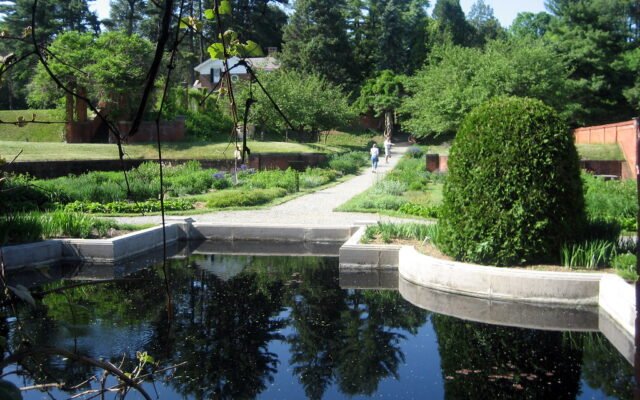 Traditioneller Bauerngarten mit Blumen, Gemüse und Wegkreuz